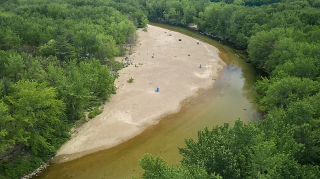 Aerial view of a river with sandy banks surrounded by lush green trees.